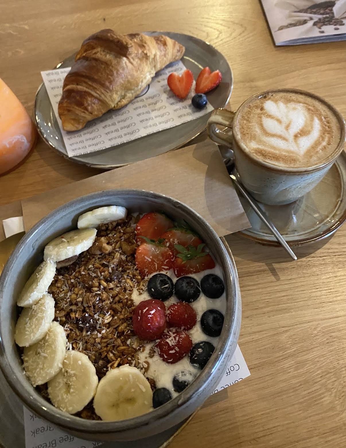 Ontbijt met croissant, granola bowl en cappuccino